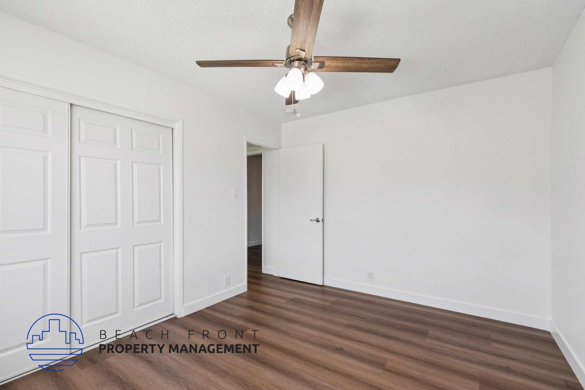 A room with a ceiling fan and wooden flooring.